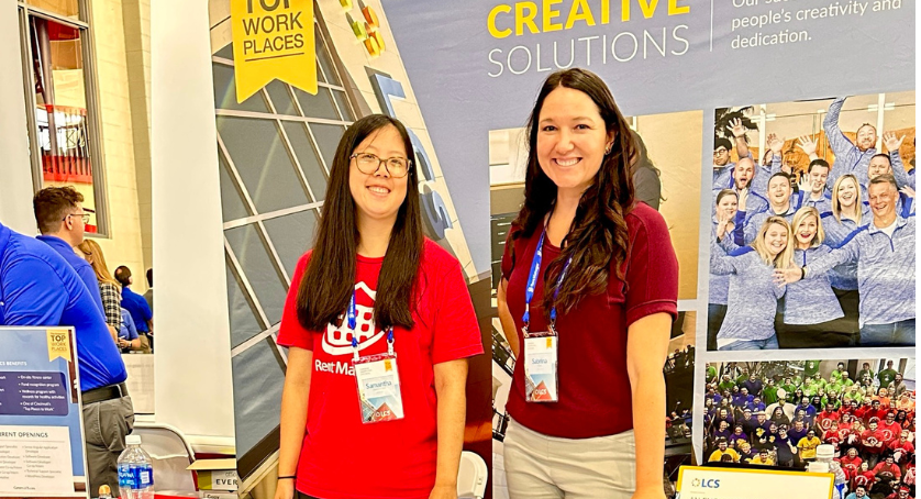 London Computer System employees smiling at a career fair, recruiting for jobs at LCS.