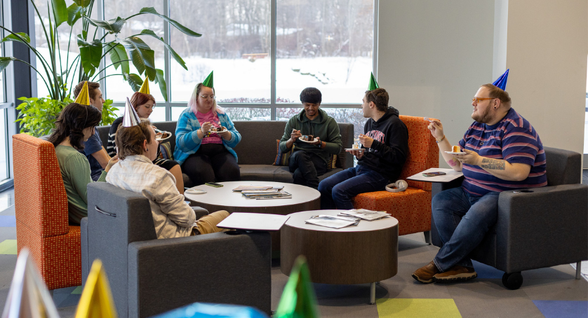 LCS employees celebrate at the office with cake and conversation around a table.